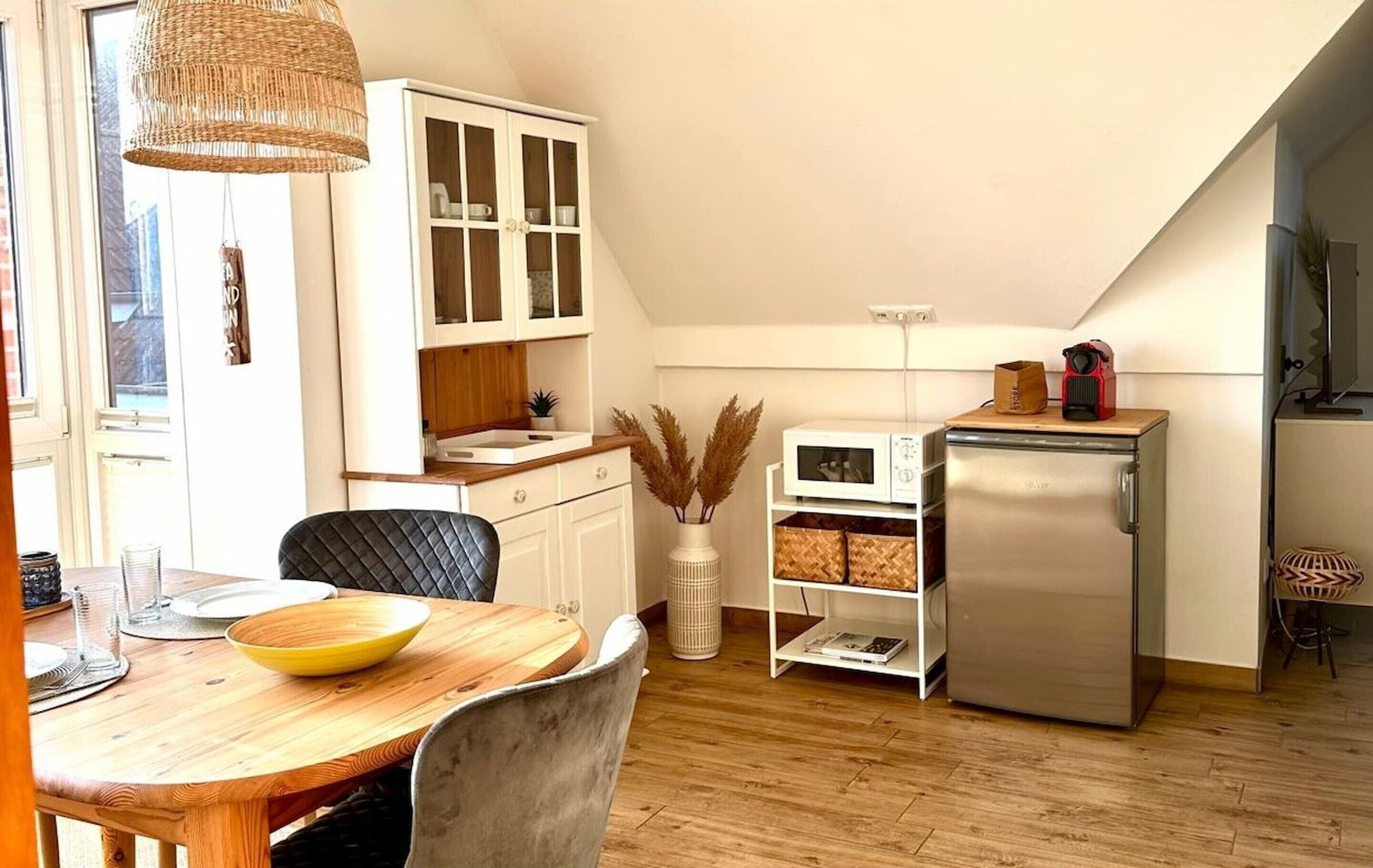 A kitchen with a dining table, chairs, a refrigerator, and cabinets.