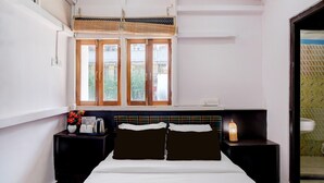 Une chambre à coucher comprenant un lit, deux tables de chevet, une commode, une fenêtre avec vue et un luminaire fixé au mur.