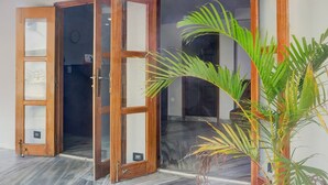 Une pièce avec une porte en bois, une plante en pot et un sol carrelé.