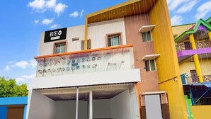 A hotel with a signboard, a covered parking area, and a multi-story building with balconies. - Deluxe Room Super Hotel O Aarapalayam (Madurai)