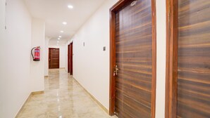 Corredor com portas de madeira, um extintor e piso revestido de azulejos.