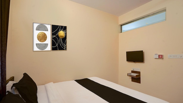 A hotel room with a bed, a TV, a power outlet, and a window. - Deluxeurban Drift (Bengaluru)