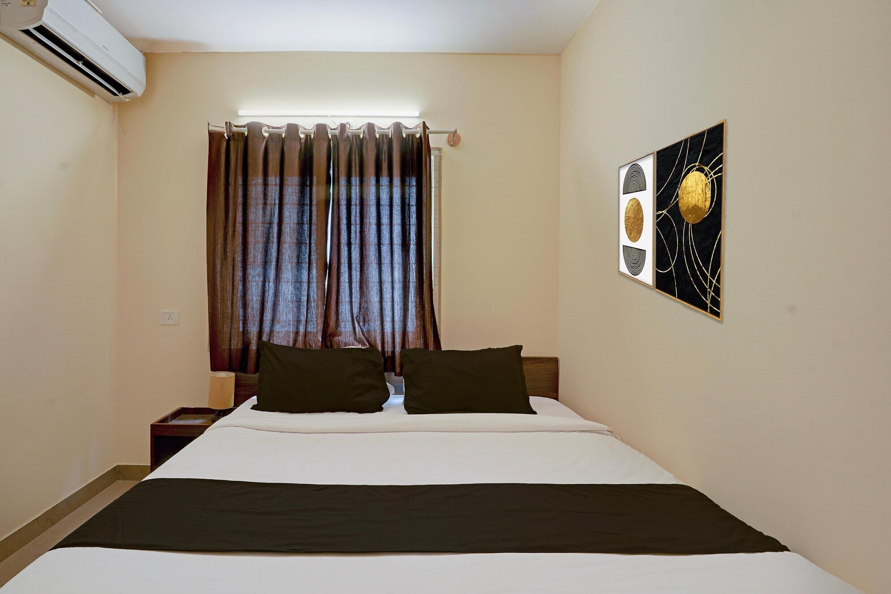 Ein Hotelzimmer mit Bett, Vorhängen, einem Wandbild und einer Klimaanlage.