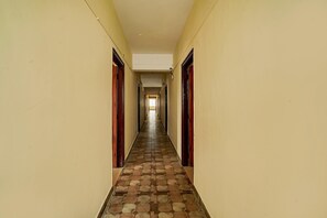 Ein langer, schmaler Korridor mit einem gemusterten Boden und Türen an beiden Seiten.