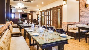 A dining area with a long table, chairs, and a brick wall. - Super Townhouse Oak Prabhat Road (Pune)