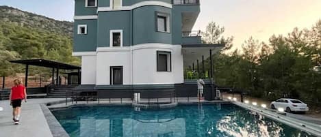 Un edificio moderno de varios pisos con una piscina al frente.