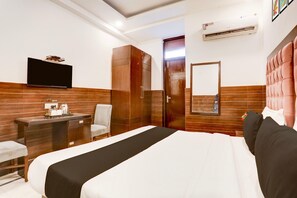 A hotel room with a bed, a desk, a chair, a television, a wardrobe, and a mirror. - Classic With Balconymahipalpur Near Airport (New Delhi)