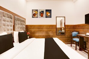 Une chambre d’hôtel avec un grand lit, une tête de lit en bois, un bureau avec une chaise et un téléviseur fixé au mur.