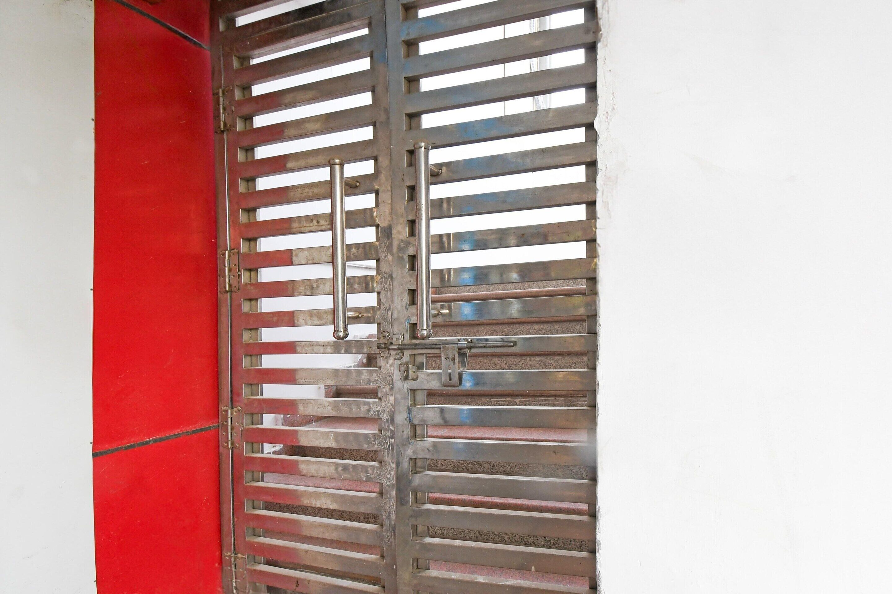 A metal gate with horizontal bars and a red vertical panel.