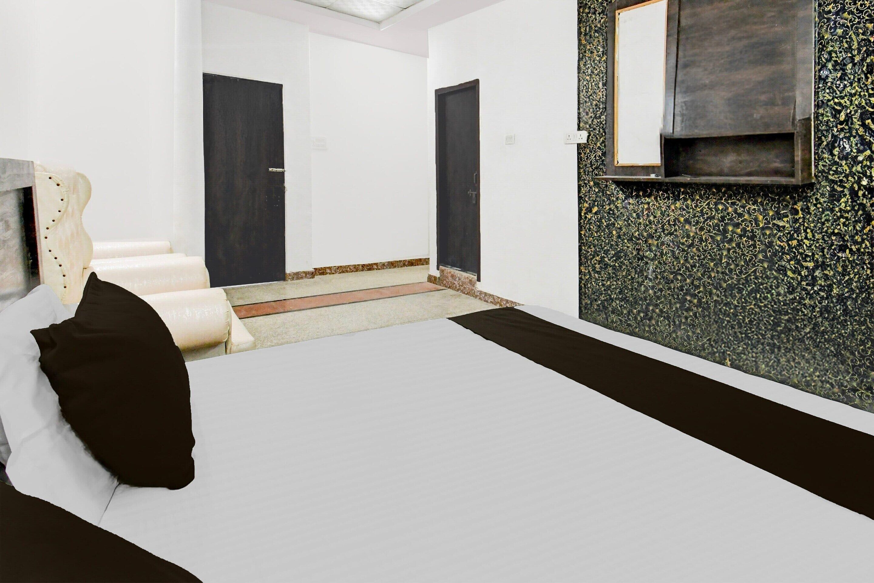 A room with a bed, a chair, a door, and a wall-mounted TV.