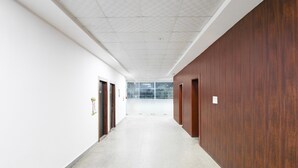 A long, narrow hallway with white walls and a wooden panel on one side. - Deluxe Khusboo Palace (Lucknow)