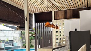 A modern interior with a ceiling fan, a poolside seating area, and a kitchen with a refrigerator.