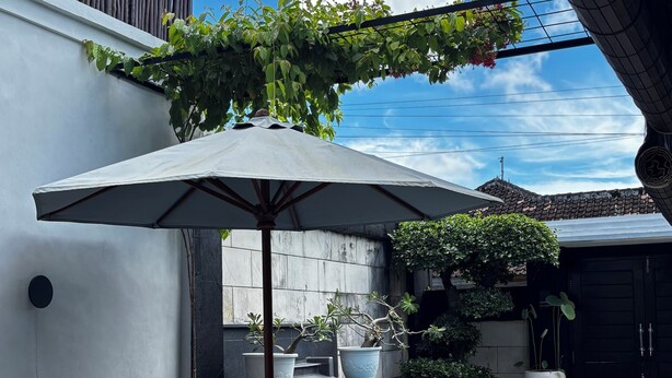 A patio with a round table, chairs, a large umbrella, and a small pool.