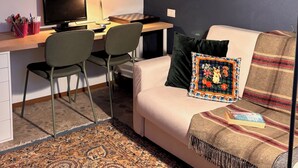 A modern living room with a desk, computer, and a couch with a decorative pillow. - A dwelling where time slows down and regain the rhythm of nature. (Morrovalle)
