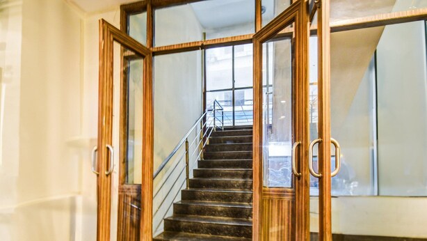 A staircase with a wooden handrail and glass doors at the top. - Super Deluxe Roomred Hills Sitara Grand (Hyderabad)
