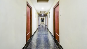 A long, narrow hotel corridor with doors on both sides, a marble floor, and a ceiling with recessed lighting. - Super Deluxe Roomred Hills Sitara Grand (Hyderabad)