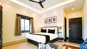 A hotel room with a bed, a table with water bottles, a ceiling fan, and a window with curtains. - Deluxe With Twin Bed Townhouse Sea Beach (Brahmagiri)