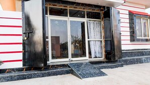 A building with a red and white facade, large glass windows, and a black door. - Deluxe With Twin Bed Townhouse Sea Beach (Brahmagiri)