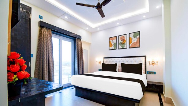 A modern bedroom with a bed, ceiling fan, artwork, and a view through the window. - Deluxe With Twin Bed Townhouse Sea Beach (Brahmagiri)