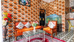 A living room with patterned walls, a sofa, a coffee table, and a TV. - Deluxe With Twin Bed Townhouse Sea Beach (Brahmagiri)