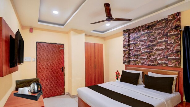 Ein Hotelzimmer mit Bett, Schreibtisch mit Tablett und Kleiderschrank, Deckenventilator und Wand mit Muster.
