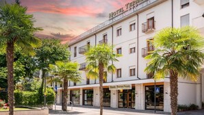 A hotel with a white facade, balconies, and palm trees in the foreground. - unity bank hotel terme padova RC12 (Abano Terme)