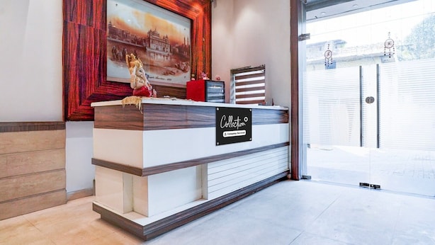 A reception desk with a framed picture above it, a clock, and a sign that reads 'Collection.' - Deluxe Hotel TR (Amritsar)
