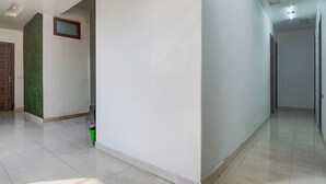 A hallway with white walls, a green accent wall, and a tiled floor. - Deluxe Hotel TR (Amritsar)