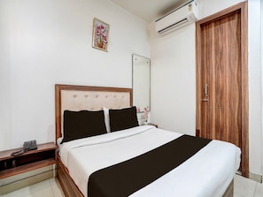 A bedroom with a bed, bedside table, mirror, and wooden wardrobe.