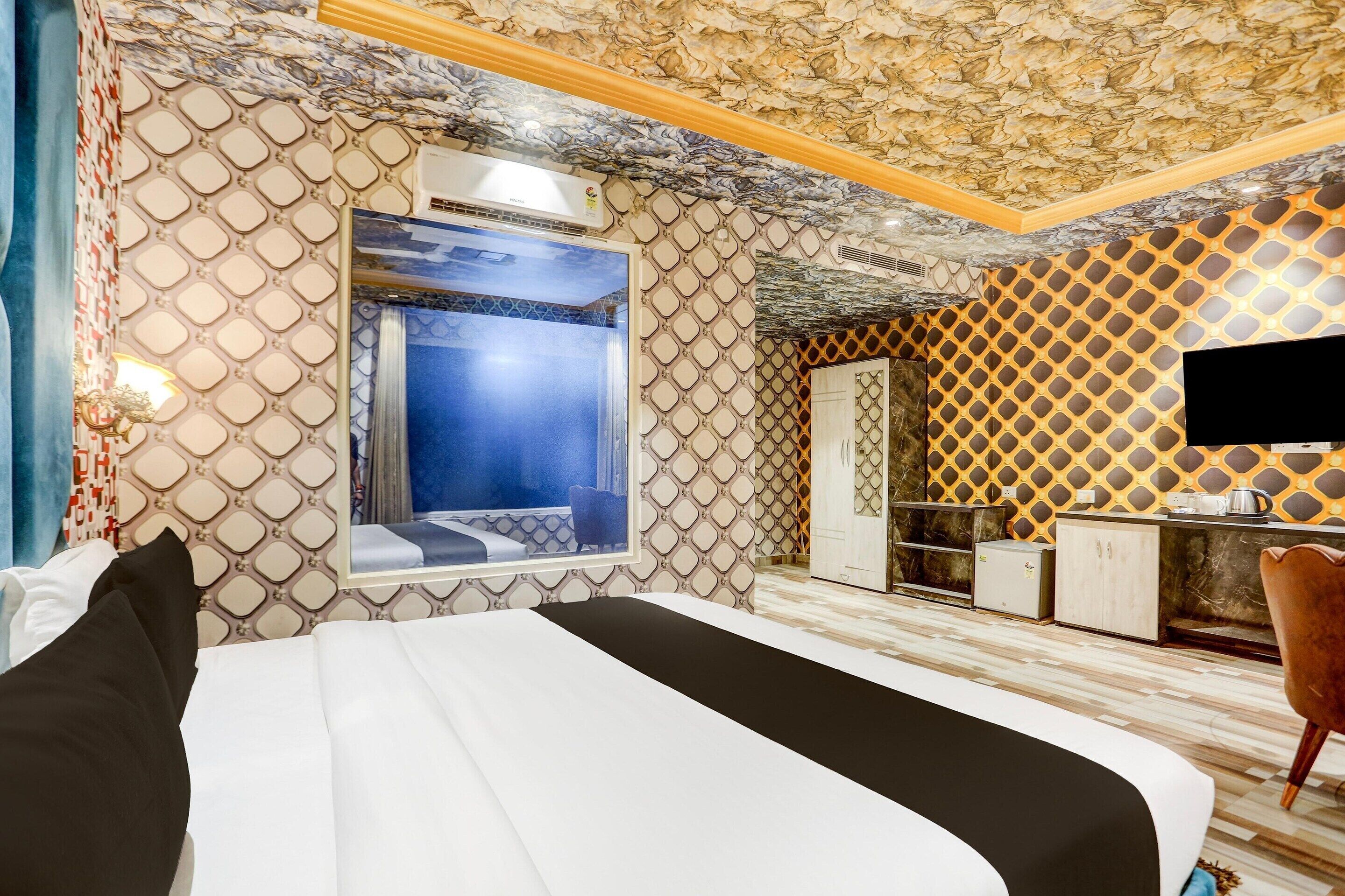 A hotel room with a bed, a large window, a wardrobe, a desk, and a television.