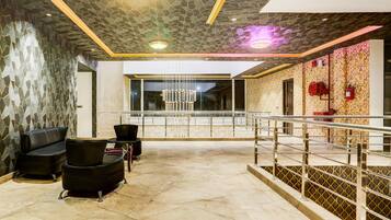 Een moderne lobby met een gedetailleerd plafond, een kroonluchter en een zithoek met zwarte stoelen.