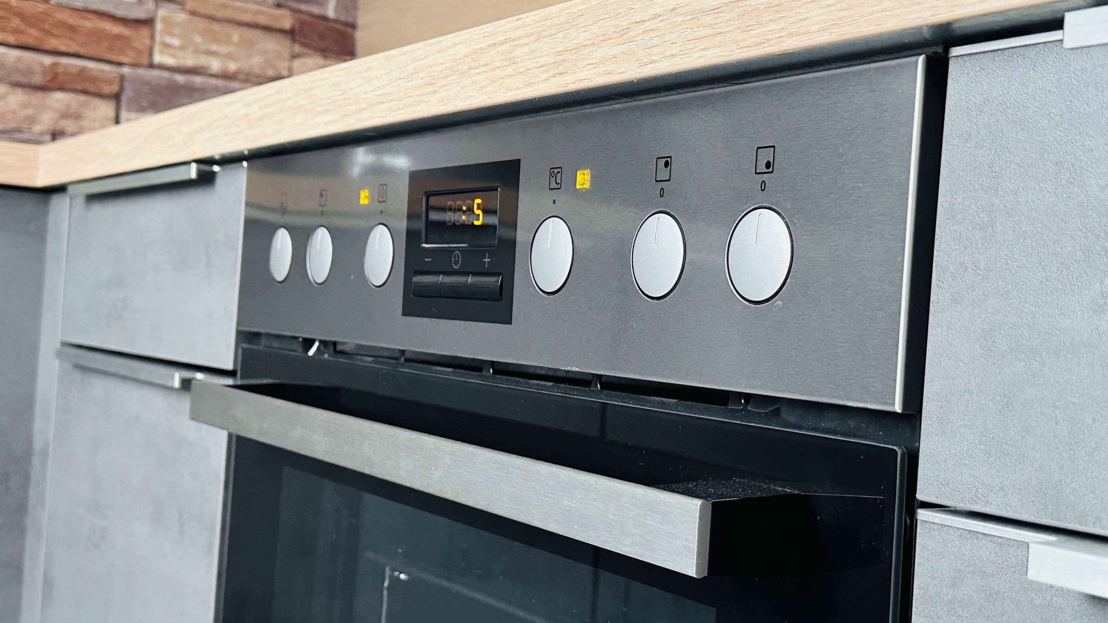 Una cucina con forno in acciaio inox, pannello di controllo digitale e piano di lavoro in legno.