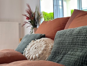 Ein Wohnzimmer mit einer Couch, Kissen und einer Topfpflanze.