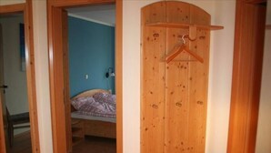A bedroom with a wooden wardrobe, a bed with a plaid blanket, and a blue wall. - Ferienwohnung in Orth auf Fehmarn (Fehmarn)