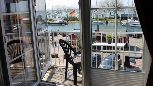A room with a view of a marina, a chair, and a table. - Ferienwohnung in Orth auf Fehmarn (Fehmarn)