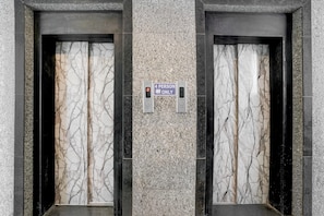 Two elevators with marble walls and a '4 PERSON ONLY' sign.