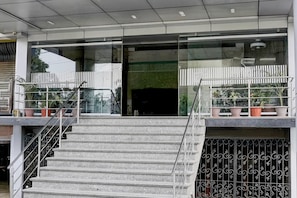 Un edificio moderno con una escalera que lleva a un balcón con plantas en macetas.