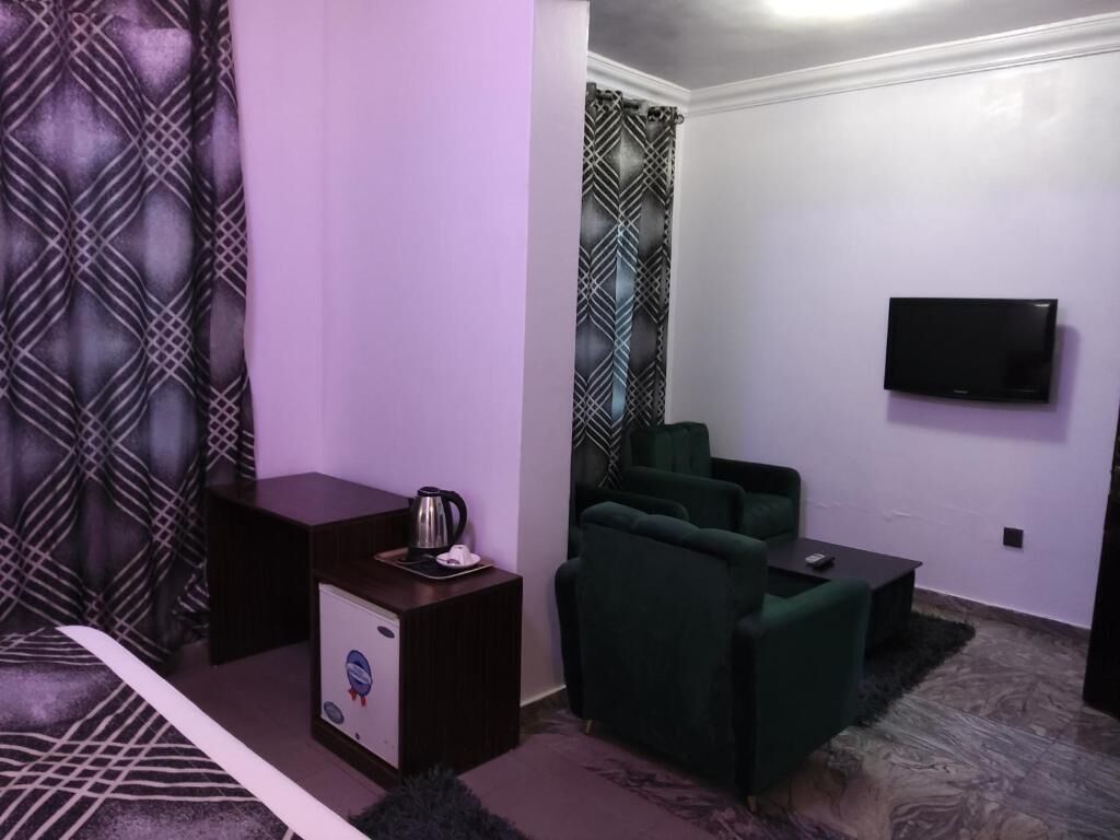 A room with a sofa, a small table, a TV mounted on the wall, and a patterned curtain.