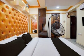 A hotel room with a tufted headboard, a bed with black and white bedding, a hanging chair, and a wooden door. - Collection O Bangalore East Railway (Bengaluru)