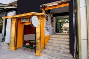 A staircase leading to a building entrance with a yellow awning and a circular sign. - Collection O Bangalore East Railway (Bengaluru)