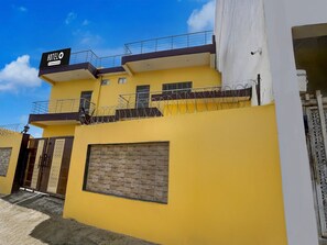 A hotel with a yellow facade, a balcony with barbed wire, and a sign indicating it is a company-serviced hotel. - Deluxesamne Ghat (Varanasi)