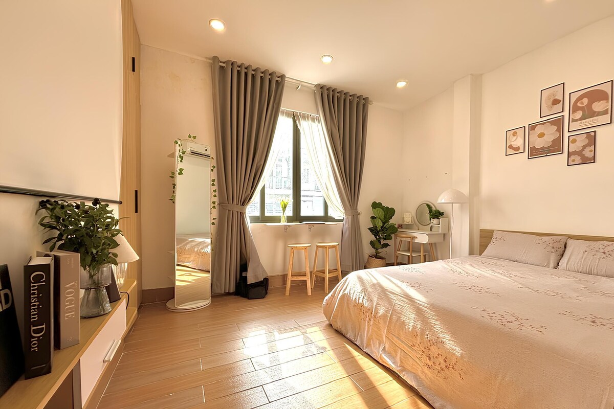 A bedroom with a bed, a desk, a chair, and a window with curtains.