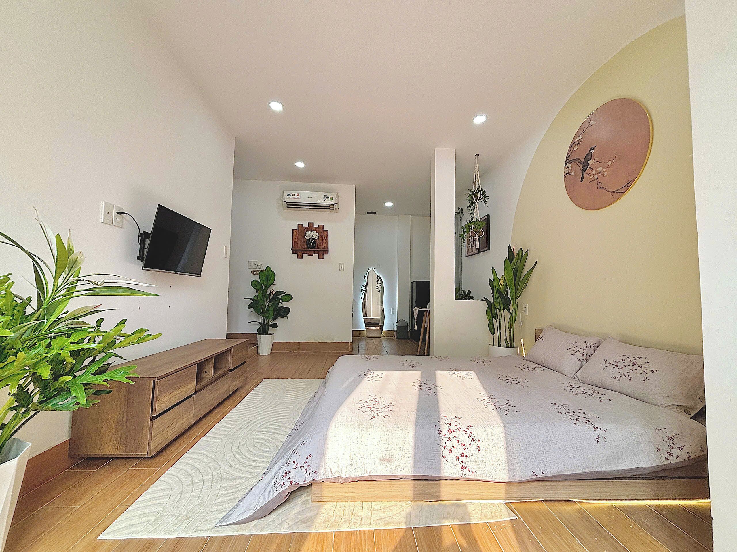 Ein geräumiges Wohnzimmer mit einem großen Bett, Holzmöbeln und einigen Blumentöpfen.