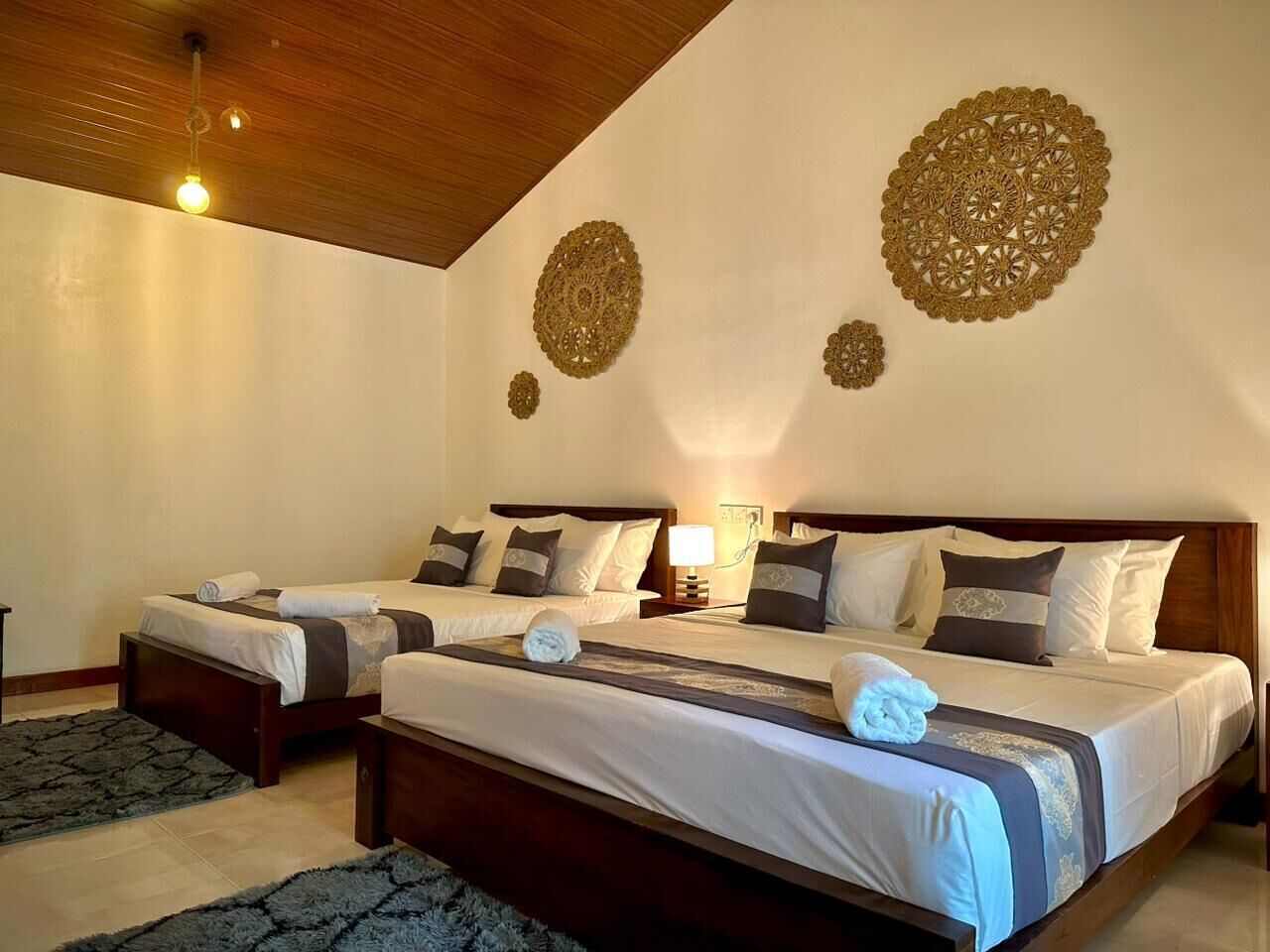 A hotel room with two beds, a wooden ceiling, and decorative wall art.
