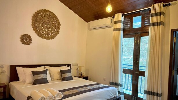Un dormitorio con cama, mesitas de noche, aire acondicionado, cortinas y un adorno en la pared.