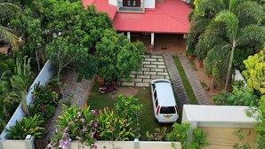 Una casa de techo rojo, rodeada de exuberante vegetación y palmeras.