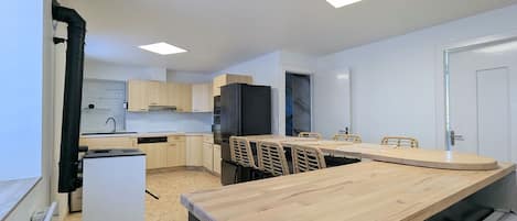 Cozinha moderna com ilha central, eletrodomésticos embutidos e área de jantar com mesa grande.