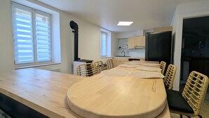 Une cuisine moderne avec une grande table en bois, des chaises en osier et un réfrigérateur noir.