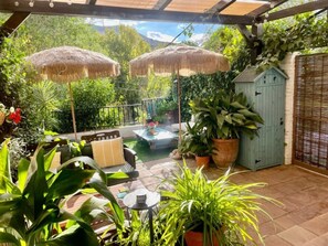 A covered patio with outdoor furniture, potted plants, and a blue shed. - Charming apartment with private terrace - 2 guests (Pinos Genil)