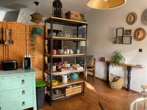 Een keuken met een houten kast, een metalen schapunit en een rieten mand.